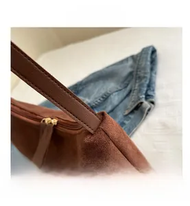 Detailed close-up of brown suede handbag stitching and golden metal zipper hardware