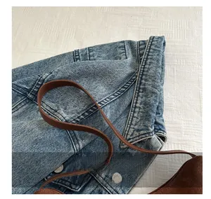 Close-up of brown suede handbag with thin strap paired with a denim jacket