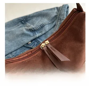 Detail of smooth metal double zippers and suede pull tabs on stylish brown shoulder bag