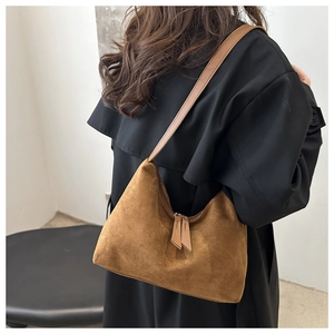 Detail of brown suede shoulder bag showing matte texture and dual leather zipper pulls