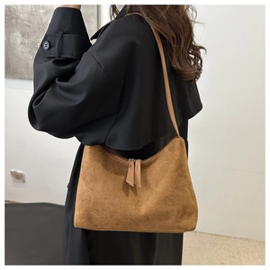 Detailed close-up of brown suede hobo bag with dual zippers and long leather pullers