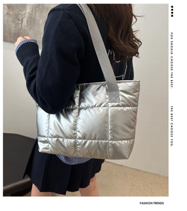 Detail of silver quilted puffer tote bag featuring glossy fabric and wide shoulder strap