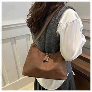 Brown suede underarm bag shown on model featuring double leather zip pullers and trapezoid shape
