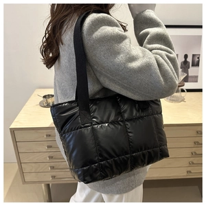 Détail du sac cabas matelassé noir brillant avec une large bandoulière en textile souple