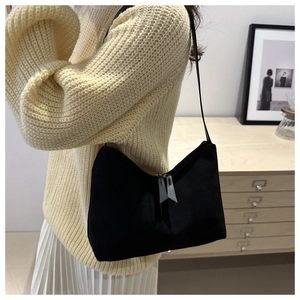 Close-up of black suede shoulder bag with dual zipper detail shown on a model