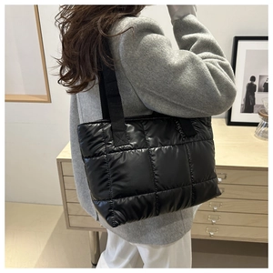 Close-up of a black quilted puffer tote bag shown on model with spacious design