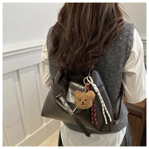 Détail du sac vintage marron avec breloque ours en peluche et accessoires en corde tissée