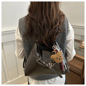 Détail du sac cabas en cuir marron foncé avec charm ours en peluche et logo mode