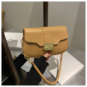 Detail of camel crocodile pattern bag featuring golden metal lock and leather strap