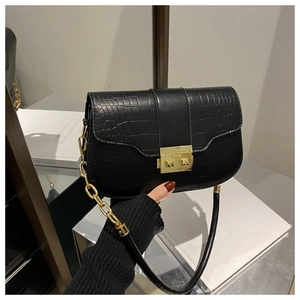 Detail of crocodile pattern leather bag with golden metal buckle and chain strap