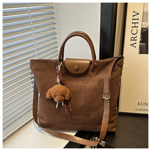 Détail du sac cabas en daim marron avec rabat en cuir et charm ours en peluche