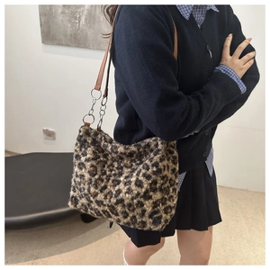 Plush leopard print tote bag with brown leather and chain shoulder strap shown on model