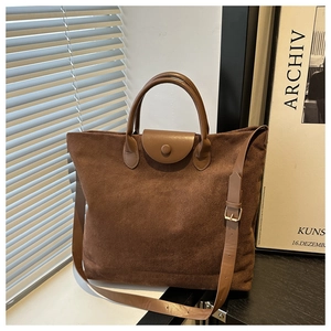 Détail de sac cabas en daim marron avec fermeture magnétique et poignées en cuir renforcées