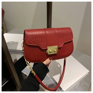Detail of red crocodile texture handbag with gold metal clasp and chain strap
