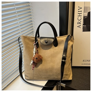 Détail du sac cabas en daim kaki avec poignées en cuir noir et pendentif chien