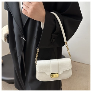 Chic white crocodile embossed shoulder bag with gold chain strap on a black coat