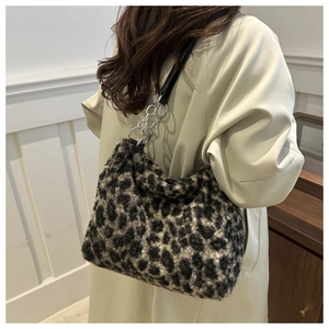 Detail of plush leopard print tote bag with silver chain strap on beige trench coat