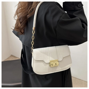 Detail of white crocodile-embossed handbag with gold buckle on a black coat back view