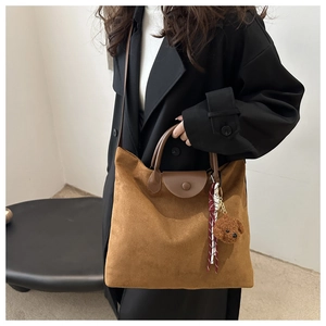 Dettaglio borsa tote in pelle scamosciata marrone con ciondolo a orsetto e foulard