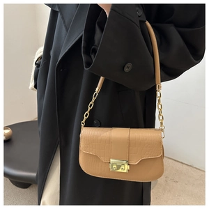 Close-up of beige croc-effect bag featuring a gold buckle and metal chain strap