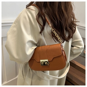 Detail of caramel crocodile pattern bag featuring gold metal lock and chain strap