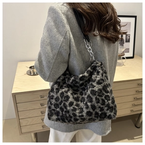 Detail of plush leopard print tote bag with silver chain strap on a model shoulder