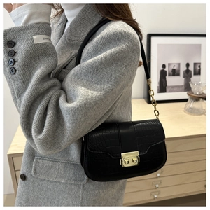 Close-up of crocodile pattern leather texture and gold square metal buckle on black bag