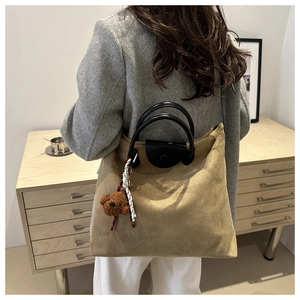 Dettaglio della borsa tote in pelle scamosciata kaki con manici e ciondolo orso