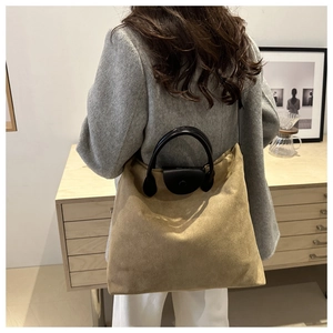 Dettaglio della borsa tote in pelle scamosciata kaki con manici in pelle nera e capienza