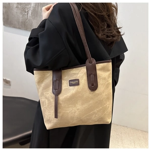 Detail of khaki canvas tote bag with brown leather handles and classic brand patch