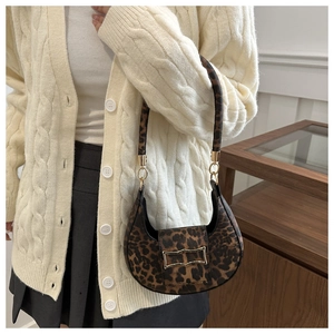 Detail of leopard print hobo bag featuring golden hardware and a textured shoulder strap