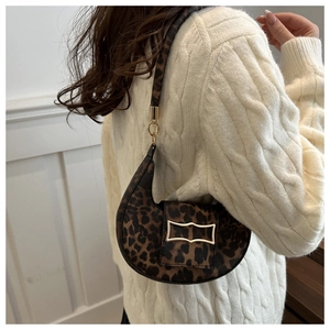 Detail of leopard print crescent bag featuring a prominent gold rectangular buckle