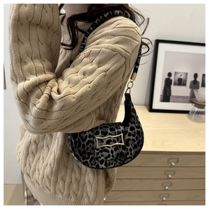 Close-up of leopard print crescent bag with gold metal buckle on a knitted sweater