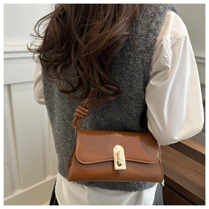 Brown leather baguette bag featuring a unique twisted knot shoulder strap and gold buckle