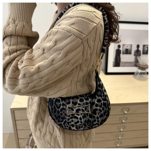 Detail of leopard print half-moon bag featuring a gold H-shaped metallic buckle clasp
