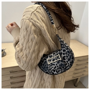 Fashionable leopard print hobo saddle bag with gold buckle worn on a shoulder