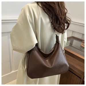 Détail du sac hobo marron foncé avec texture craquelée vintage et bandoulière à chaîne