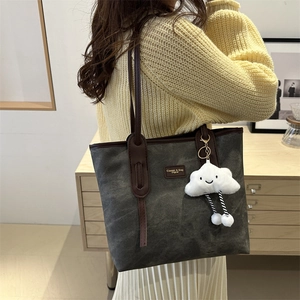 Large gray vintage tote bag with brown leather handles and a cloud charm on a model