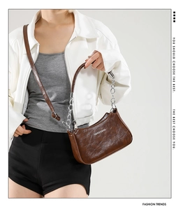 Detail of brown faux leather hobo bag with silver chain and white fashion text logo