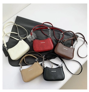 Top view of five colorful crescent shoulder bags with leather straps and silver chains