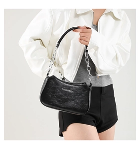 Detail of black crescent shoulder bag with pleated texture and metal chain strap