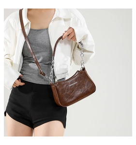 Brown vintage leather crescent bag with chain handle shown on model in minimal styling