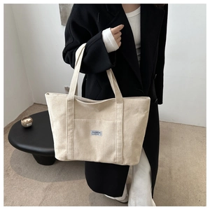 Detail of cream corduroy tote bag showing vertical texture and Fashion woven label
