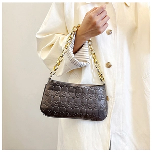 Close-up of embossed skull pattern shoulder bag with a textured gold chain strap