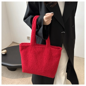 Detail of red faux shearling tote bag with soft plush texture and matching handle