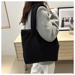 Macro shot of fluffy black plush tote bag texture with matching soft shoulder straps