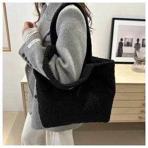 Close-up of black sherpa fleece tote bag showing soft fuzzy texture and wide shoulder strap