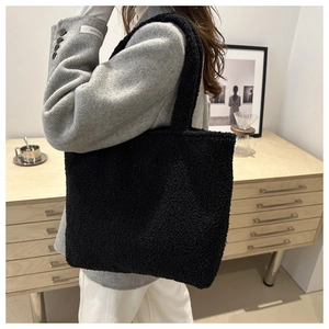 Detail view of large black plush tote bag with soft fleece texture on a fashion model