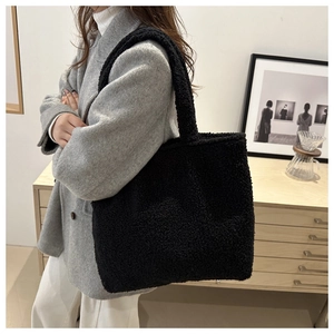 Winter black plush tote bag shown on shoulder in a stylish minimalist setting
