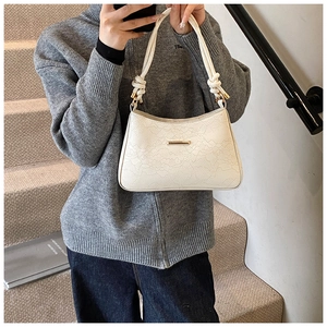 Detail of white PU leather underarm bag with lace embossing and round rope handle